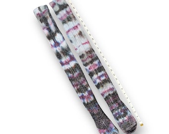 May include: A pair of long, black and white socks with a tie-dye pattern in shades of pink, purple, and blue. The socks are made of a soft, fuzzy material.