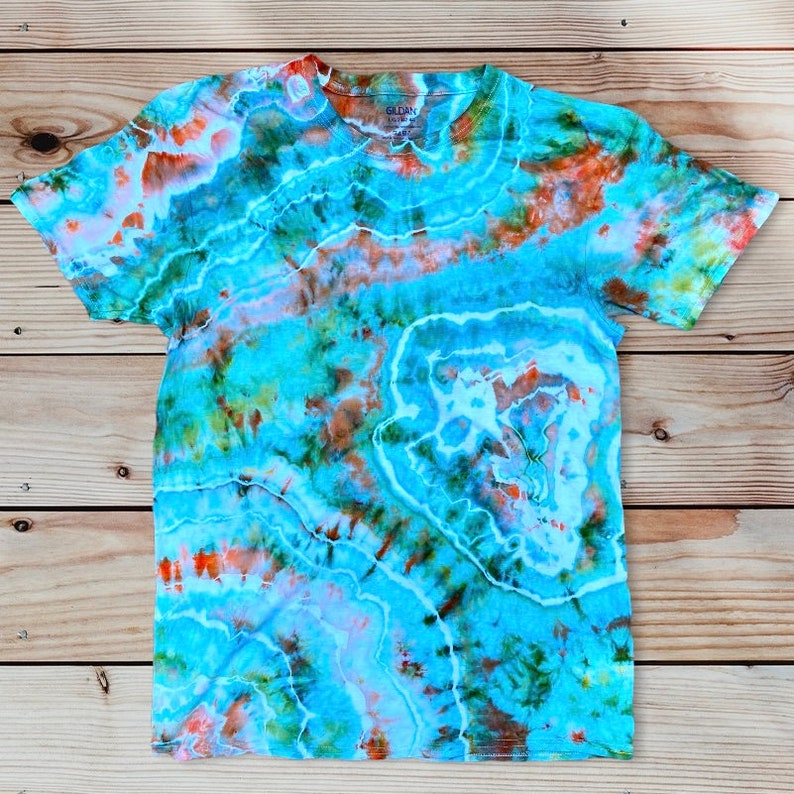 May include: A tie-dye t-shirt with a blue, green, orange, and white swirl pattern. The shirt has a crew neck and short sleeves.