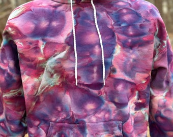 May include: A purple, pink, and blue tie-dye hoodie with a white drawstring. The hoodie has a kangaroo pocket.