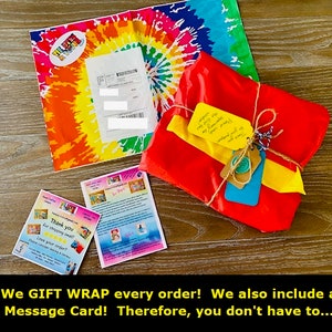 May include: A gift-wrapped package with red wrapping and a yellow tag tied with twine, on a wooden surface. Beside it is a tie-dye envelope and a thank you card. The card says "Thank you for shopping small".