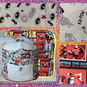 May include: A collection of fabric items featuring cartoon characters and comic book panels. The items include a cylindrical storage container with a pocket, a pillow, and a rectangular piece. The fabrics display vibrant colors and text like "KA-POW" and "SAVING THE DAY".