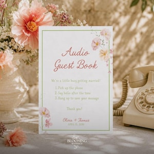 以下が含まれることがあります： 緑の縁取りと花のアクセントが施された白い長方形のサイン。Audio Guest Bookという文字、使用説明、Olivia + Thomasという名前と2025年4月15日という日付が記載されており、クリーム色のヴィンテージな回転式電話機の横に置かれています。