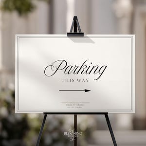 May include: A rectangular white sign with a thin black border, featuring the black text Parking THIS WAY, a black arrow pointing right, and the names Olivia & Thomas with the date 12.06.2026 printed at the bottom, displayed on a black easel.