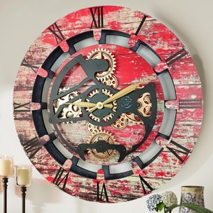May include: A large, round, red and black wall clock with a distressed wood-look finish. The clock face features Roman numerals and a detailed gear design with gold accents.