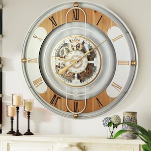 May include: A large, round, white and wood clock with Roman numerals and a visible gear mechanism. The clock has a white face with gold accents and a wood frame.