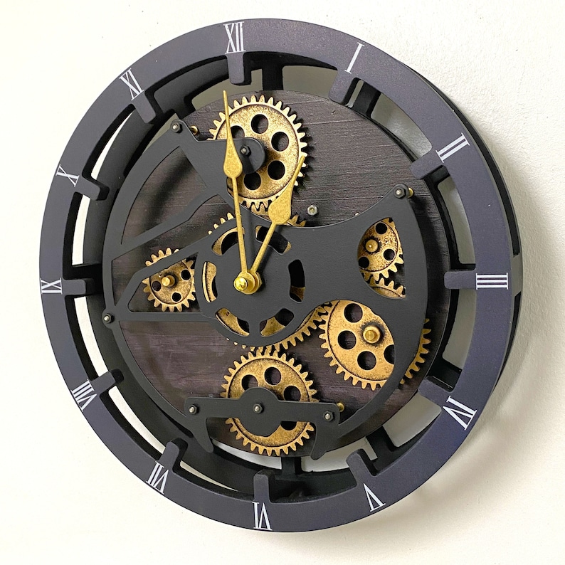 May include: Black clock with Roman numeral markings and gold gears. The clock face is surrounded by a black frame with a wood-like background.