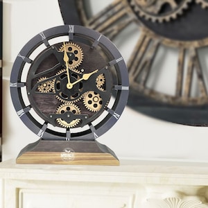 May include: A black and gold steampunk-style clock with Roman numeral markings and a wooden base. The clock features intricate gears and a dark wood background.