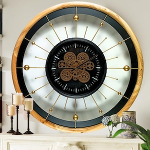 May include: A large, round, wooden framed clock with a black face and gold gears. The clock has a white background with gold accents and a silver ring around the edge.