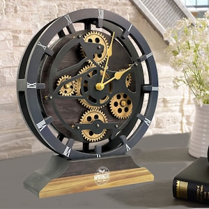 May include: A black and gold tabletop clock with Roman numeral markings and a visible gear mechanism. The clock has a wooden base with the text "ImprovingLife" printed on it.
