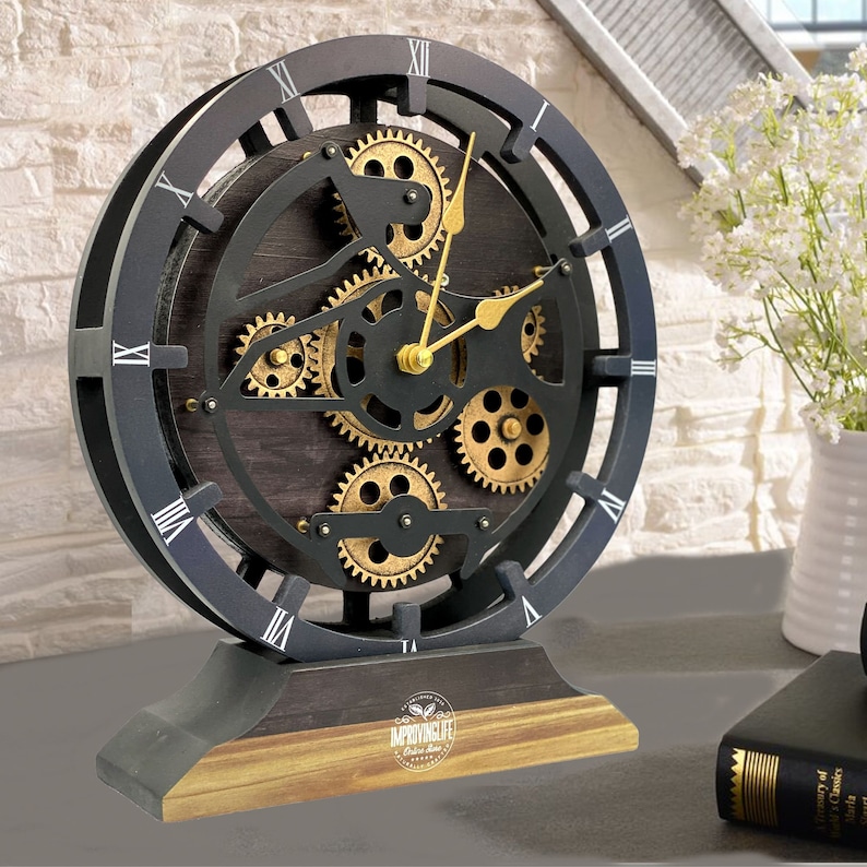 May include: A black and gold tabletop clock with Roman numeral markings and a visible gear mechanism. The clock has a wooden base with the text "ImprovingLife" printed on it.