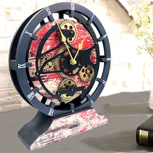 May include: A black and red clock with a distressed wood-look design. The clock face features a circular design with gears and Roman numerals. The clock is on a black stand with a distressed wood-look design.