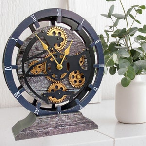 May include: A black and gold clock with a wooden base and a gear design. The clock face has Roman numerals and the words "Timeless" printed on the base.