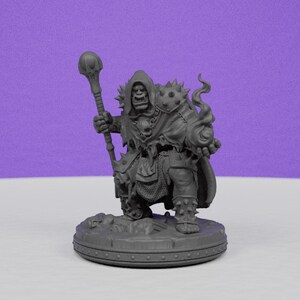 May include: A gray miniature figurine of a fantasy character, possibly an orc, holding a staff and a flaming orb. The figure is wearing armor and a hooded cloak, standing on a circular base. The background is a solid purple.