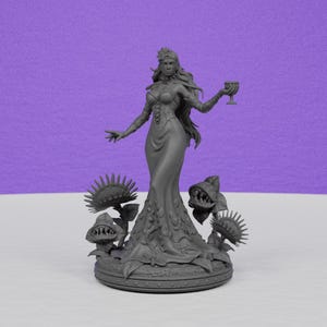 May include: A gray figurine of a woman in a long dress, holding a goblet. The figure is surrounded by stylized carnivorous plants. The base is round with a decorative border. The background is a solid purple.