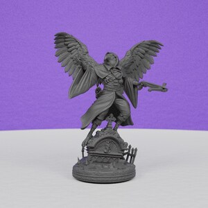 May include: A gray figurine of a winged humanoid figure, holding a gun, standing atop a tombstone. The figure has large, detailed wings and is dressed in a long coat and hat. The base of the figurine is a circular platform with a detailed graveyard scene.