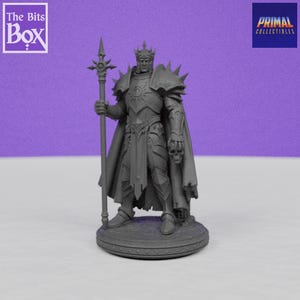 May include: A gray miniature figurine of a king in armor, holding a staff with a decorative top. The king wears a crown and cape, and stands on a circular base. The figurine has a skull on the right arm. The Bits Box and Primal Collectibles logos are visible.