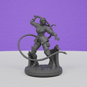 May include: A gray figurine of a woman in a dynamic pose, holding a whip. She wears a fitted jacket, pants, and boots. The figure is on a circular base with a detailed design, suggesting a fantasy or historical theme.