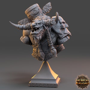 May include: A gray, detailed bust of a minotaur-like creature with horns, a beard, and a braided mane. The creature is wearing armor and holding a weapon. The bust is on a gray pedestal with a decorative base.