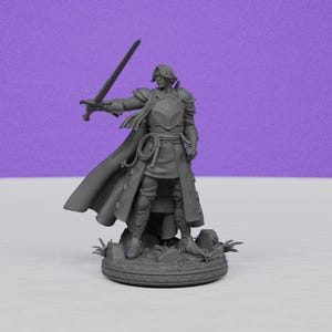 May include: A gray figurine of a knight in armor, holding a sword aloft. The knight wears a long coat and cape, with a shield on the chest. The figure stands on a circular base with a detailed design, set against a purple background.