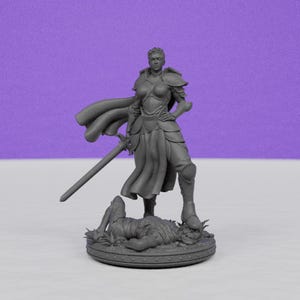 May include: A gray figurine of a warrior in armor, holding a sword and standing over a defeated creature. The warrior wears a cape and stands on a circular base with detailed carvings. The background is a solid purple.