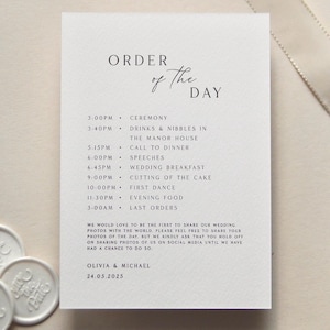 May include: A cream-coloured wedding order of the day card with black text. The card lists the ceremony, dinner, speeches, and other events. The card also includes the names Olivia & Michael and the date 24.05.2025.