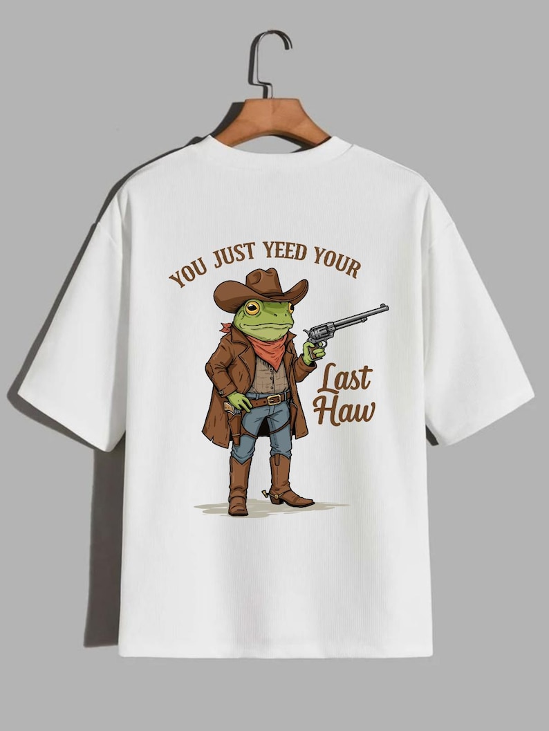 May include: White t-shirt with a cartoon frog wearing a cowboy hat and holding a gun. The text "You just yeed your last haw" is printed on the back of the shirt.
