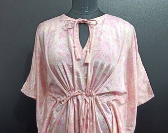 May include: A pink and white patterned kaftan with a tie at the waist and a keyhole neckline. The kaftan has a loose fit and is made of a lightweight fabric.