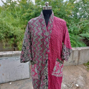 May include: A pink and gray quilted kimono with a floral print and two patch pockets. The kimono is on a mannequin.