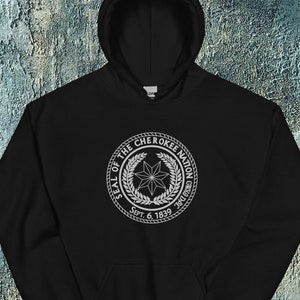 May include: Black hooded sweatshirt with a white graphic of the Seal of the Cherokee Nation. The seal features a star with a circle of leaves around it and the text "Seal of the Cherokee Nation" and "Sept. 6, 1839".