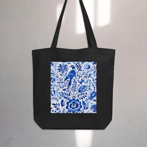 Puede incluir: Bolsa de tela negra con un patrón floral azul y blanco con un pájaro. El patrón recuerda a la tradicional cerámica holandesa de Delft.