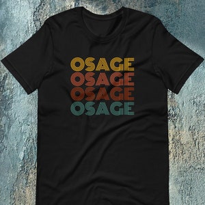 May include: Black t-shirt with the word "OSAGE" repeated four times in a retro, multi-colored font.