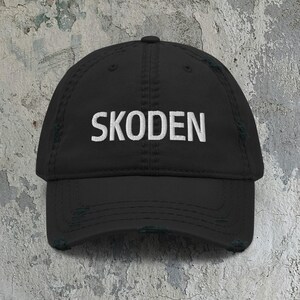 Könnte beinhalten: Schwarze Baseballkappe im Used-Look mit dem Wort "SKODEN" in Weiß gestickt. Die Kappe hat einen gebogenen Schirm und einen abgenutzten, Vintage-Look, ideal für Freizeitkleidung.