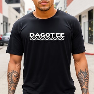 May include: A black t-shirt with a white graphic design that says "DAGOT'EE" with a wavy line underneath.