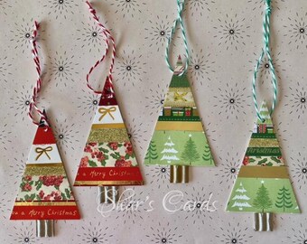 May include: Four triangular Christmas tree ornaments made of layered paper strips with gold accents, holly patterns, and pine tree illustrations. Each ornament features a metallic base and a hanging string in red-white or green-white twisted cord.