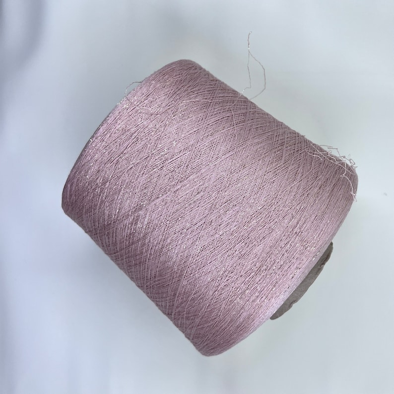 May include: A spool of light pink yarn with a subtle shimmer.