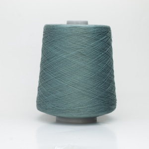 Op de afbeelding: Een teal-kleurige garenkegel, ideaal voor brei- of haakprojecten. Het garen is strak gewikkeld rond een cilindrische basis, waardoor een conische vorm ontstaat. De kegel staat op een grijze basis tegen een witte achtergrond. Het garen ziet er zacht en klaar voor gebruik uit.