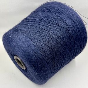 Peut inclure: Une grosse bobine de fil bleu marine. Le fil est étroitement enroulé autour d'un noyau en carton avec un anneau métallique à la base. Le fil semble être une fibre naturelle, avec une surface légèrement texturée. Idéal pour les projets de tricot et de crochet.