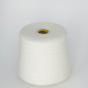 Puede incluir: Un cono de hilo blanco con un agujero central amarillo.