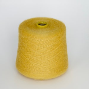 Puede incluir: Una bobina de hilo amarillo, lista para tejer o hacer ganchillo.