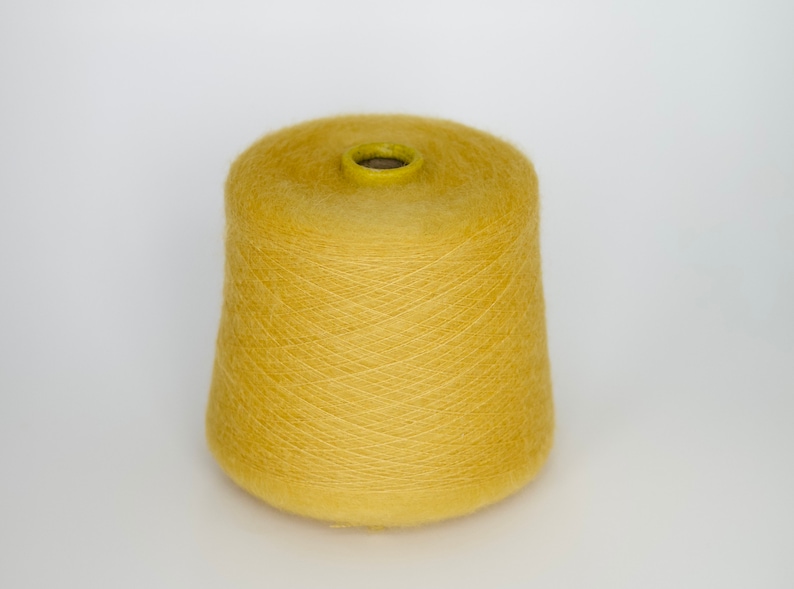 Puede incluir: Una bobina de hilo amarillo, lista para tejer o hacer ganchillo.