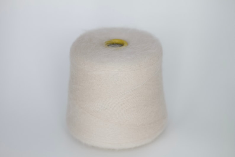 Puede incluir: Un cono de hilo beige p&aacute;lido con un centro amarillo.