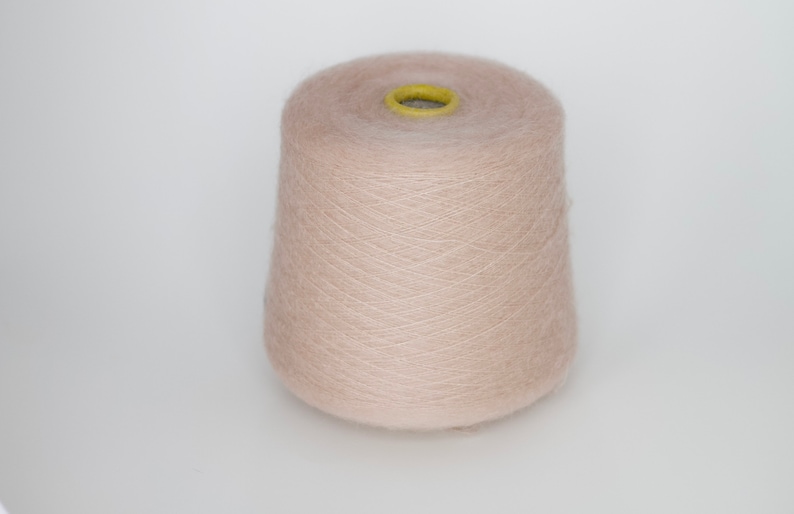 Puede incluir: Un ovillo de hilo de color marr&oacute;n claro, enrollado en un carrete de cart&oacute;n.