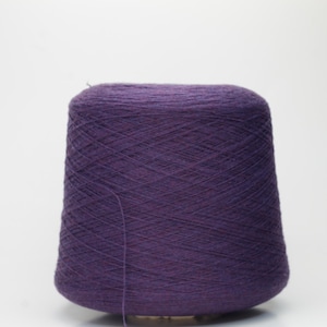 May include: A large cone of deep purple yarn, ideal for knitting or crocheting projects. The yarn is tightly wound, creating a smooth, textured surface. The cone is set against a plain white background.