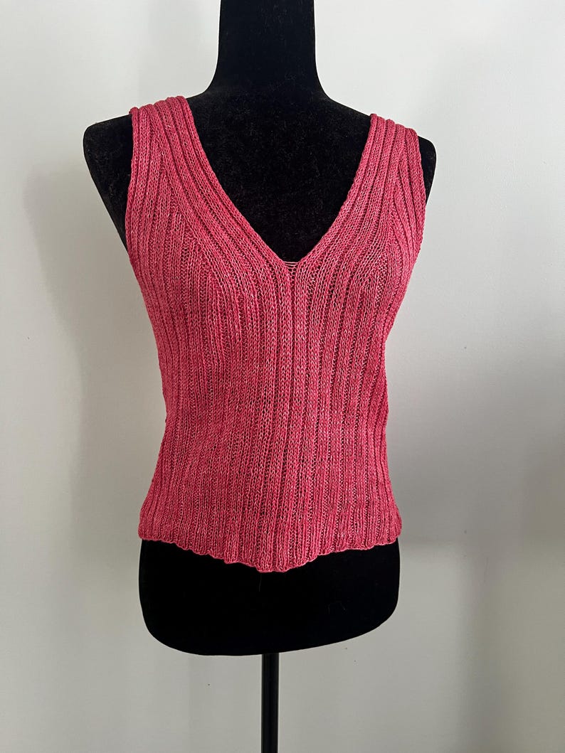 May include: A sleeveless pink knitted top with a V-neckline.