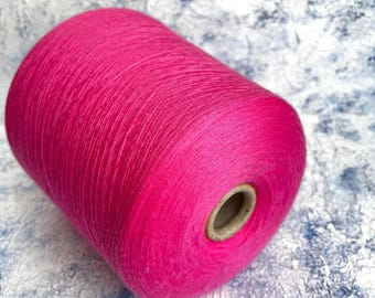 May include: A vibrant pink yarn cone, tightly wound and cylindrical in shape. The yarn is a solid, saturated color, with a slight sheen. The cone has a cardboard core. Ideal for knitting, crocheting, and other fiber arts projects.