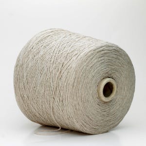Peut inclure: Une grosse bobine de fil gris clair. Le fil est étroitement enroulé autour d'un noyau en carton, créant une forme cylindrique. Le fil semble être une fibre naturelle, avec une surface légèrement texturée. Le fond est blanc uni.
