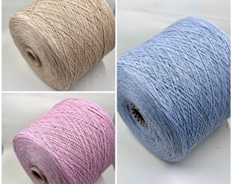 May include: Three spools of yarn in different colours: beige, light blue, and pink. The yarn is a soft, textured material.