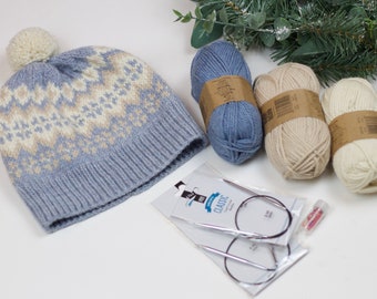 May include: A blue and white knitted hat with a pom-pom on top, three balls of yarn in blue and white, and a pair of circular knitting needles in a plastic package.