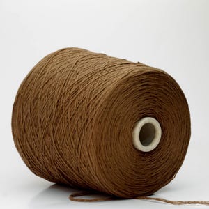 Peut inclure: Une grosse bobine de fil marron, bien enroulée. Le fil est d'une teinte chaude et terreuse, idéal pour le tricot, le crochet ou d'autres projets de fil. La bobine a un noyau blanc.