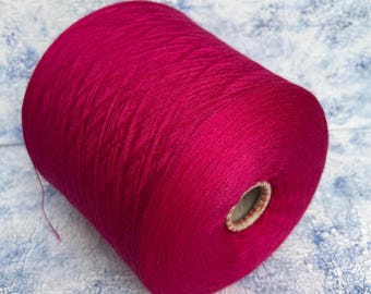 May include: A large spool of vibrant fuchsia yarn. The yarn is tightly wound, creating a smooth, cylindrical shape. The core of the spool is visible at one end. The yarn is a solid color, ideal for knitting, crocheting, or other fiber arts projects.